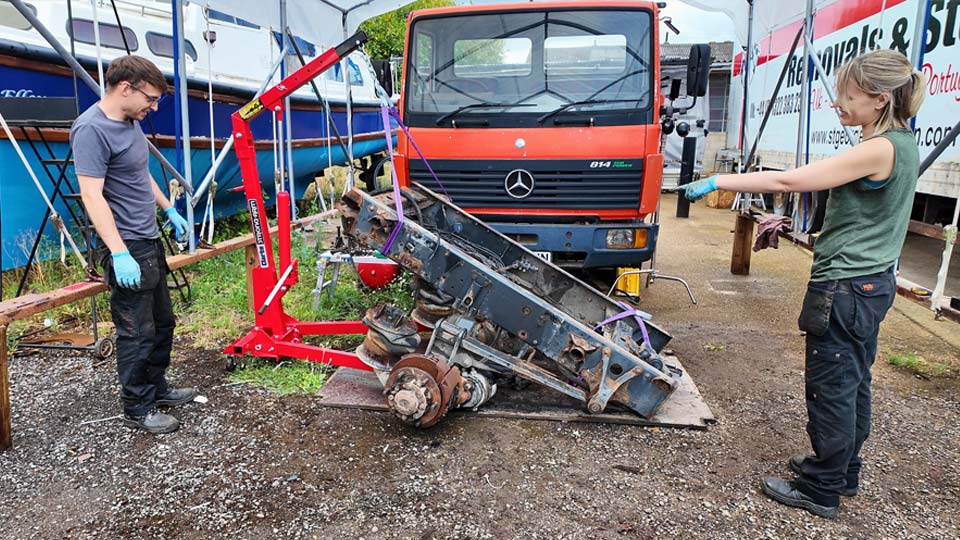 Hayley and Pete ussing a crane to lift the chassis rails from the suspension and axle