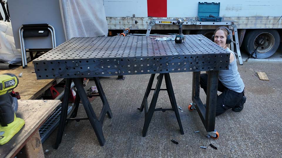 Hayley adds massive steel legs to the underside of a newly built welding fixture table