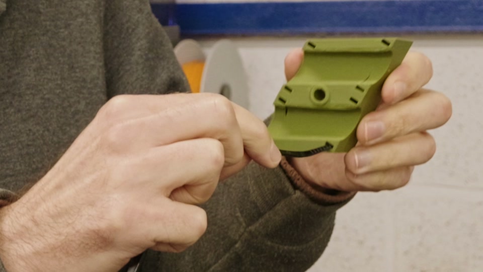 Pete showing the zip-tie channel on a green 3D-printed cable bracket for the tiny house trailer chassis