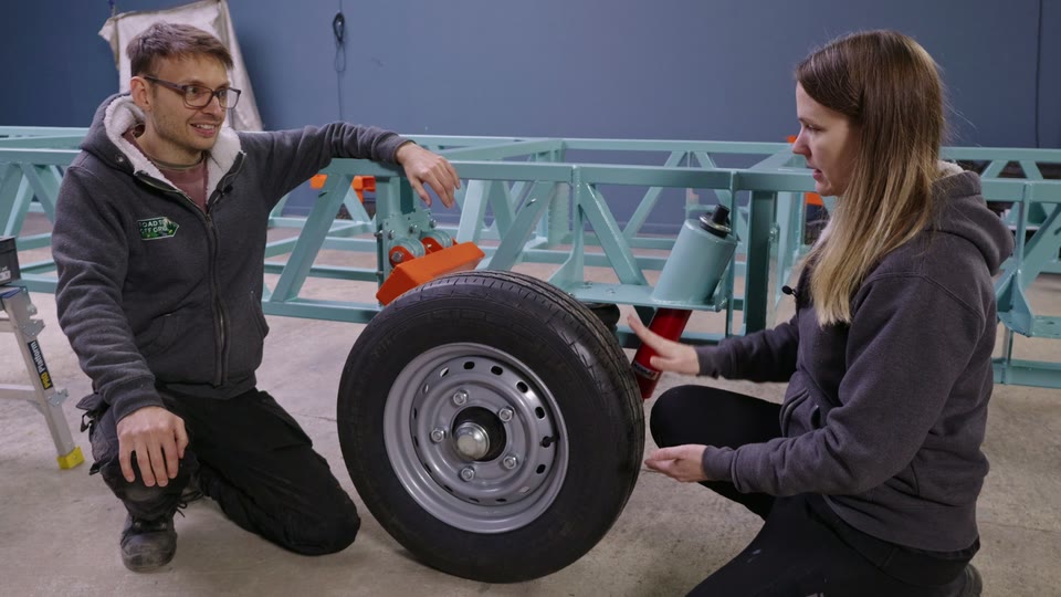 Pete and Hayley either side of the first wheel fitted to the tiny house trailer's new air suspension