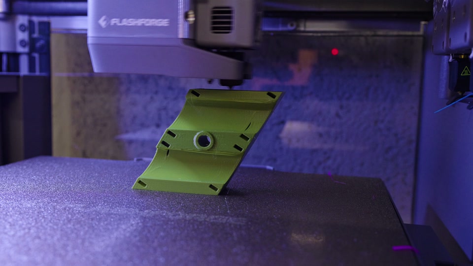 Flashforge Creator 5 Pro 3D printer toolhead printing a green cable bracket for our tiny house trailer chassis